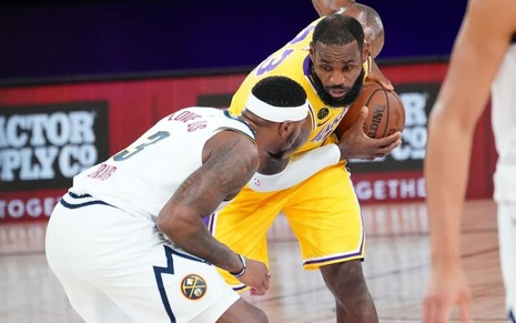 Imagem de LeBron James, dos Lakers, se preparando para driblar Torrey Craig, dos Nuggets, em jogo da NBA