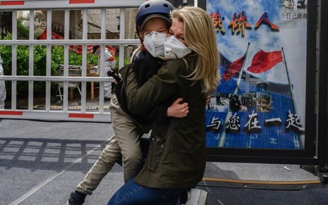 Janis Mackey Frayer e filho se abraçam, ambos usando máscaras cirúrgicas, na cidade de Pequim