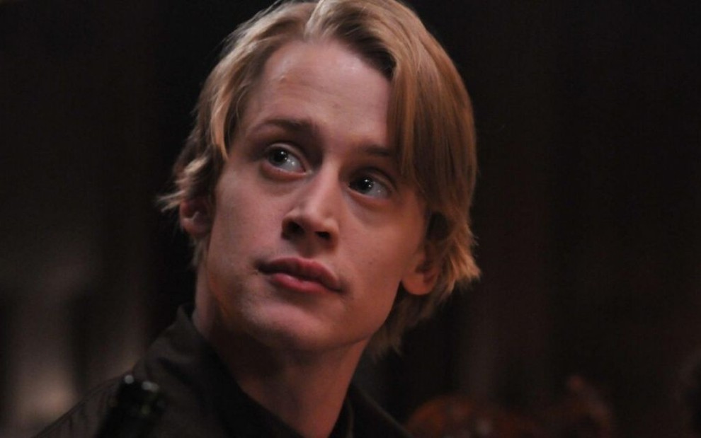 Ator Macaulay Culkin, com cabelos loiros penteados, olha para cima em cena da série Kings