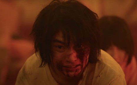 O personagem Arisu (Kento Yamazaki) olha com rosto machucado e ensanguentado na série Alice in Borderland