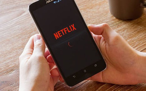 Imagem das mãos de um usuário esperando o carregamento do aplicativo da Netflix