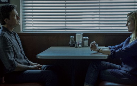 Os atores Jason Bateman e Laura Linney se encaram sentados em uma mesa de lanchonete