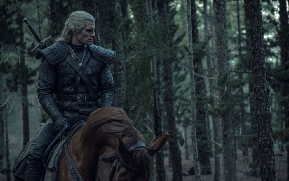 O ator Henry Cavill no papel do bruxo Geralt vestindo armadura e sentado em um cavalo