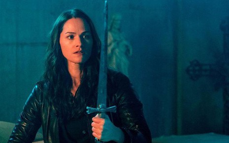 A atriz Kelly Overton observa uma espada em cena da série Van Helsing