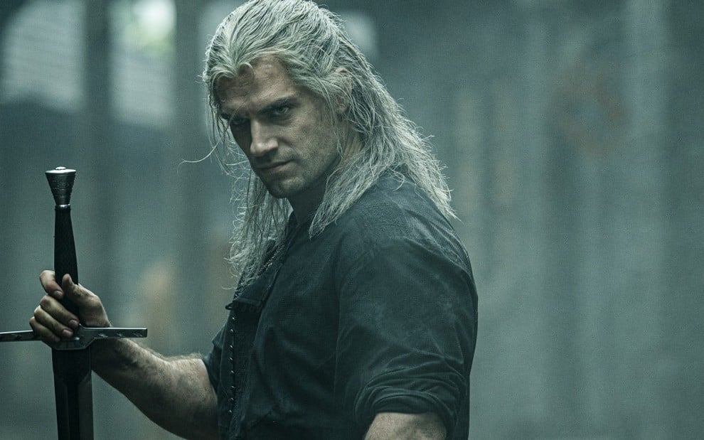 Henry Cavill, com a peruca branca e a espada do bruxo Geralt de Rivia, em cena da série The Witcher, da Netflix