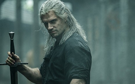Henry Cavill, com a peruca branca e a espada do bruxo Geralt de Rivia, em cena da série The Witcher, da Netflix