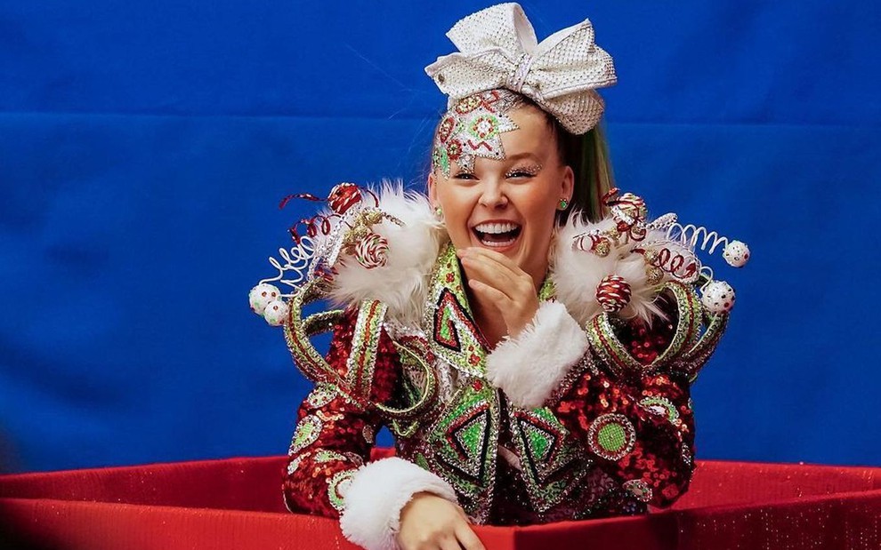 Vestida com ornamentos natalinos e seu tradicional laço na cabeça, JoJo Siwa ri muito em foto de seu Instagram