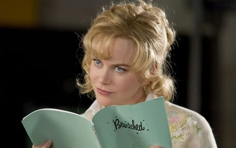 A atriz Nicole Kidman sorri enquanto lê um roteiro em cena do filme A Feiticeira (2005)