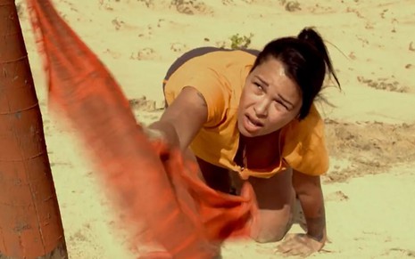 Imagem de Ariadna Arantes segurando bandana em duna durante cena do No Limite 5