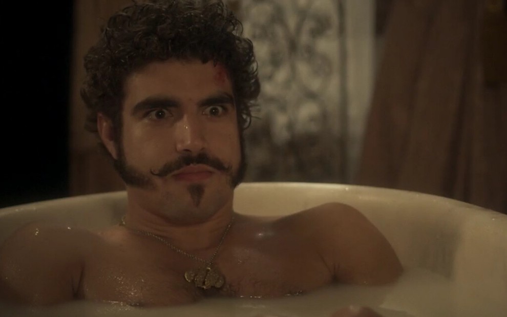 Personagem de Caio Castro em Novo Mundo, dom Pedro arregala os olhos enquanto está em uma banheira