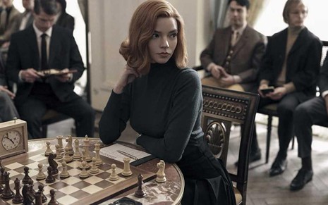 Com seus cabelos ruivos, a personagem Beth Harmon, interpretada por Anya Taylor Joy, olha para o lado durante partida de xadrez na série O Gambito da Rainha