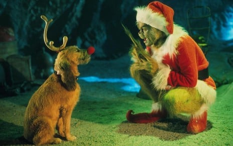 Usando um galho na cabeça e um nariz vermelho, o cãozinho Max encara o Grinch (Jim Carrey) vestido de Papai Noel