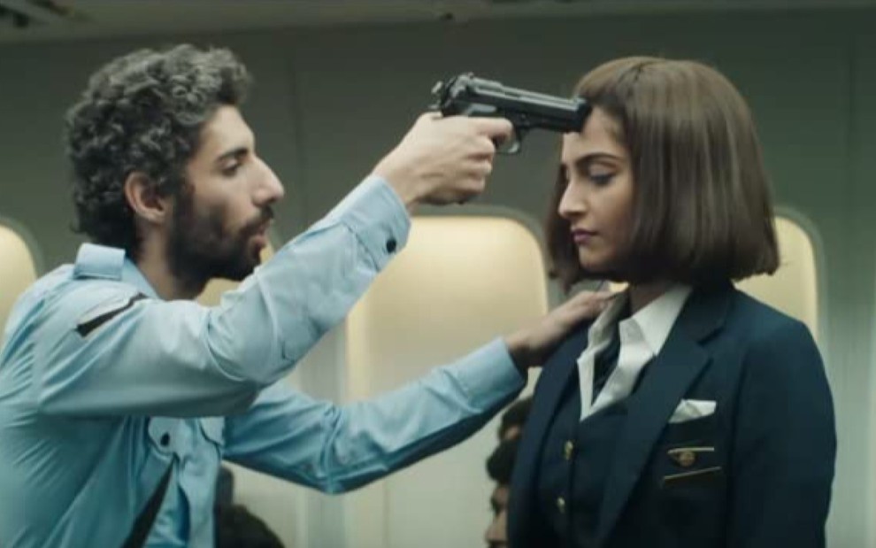 Um homem com uma arma apontada para a cabeça de Sonam Kapoor, que está com os olhos fechados