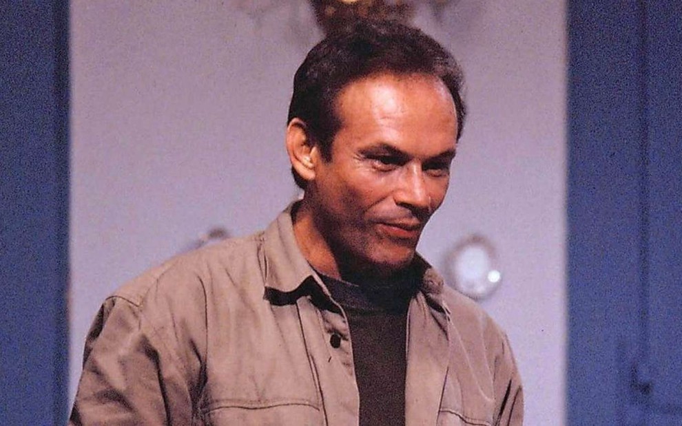 O ator José Wilker (1944-2014) olha para a direita, com expressão levemente sorridente, em cena em estúdio da novela O Salvador da Pátria