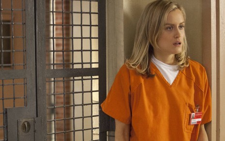 Uma assustada Taylor Schilling veste um uniforme laranja de presidiária na série Orange Is the New Black