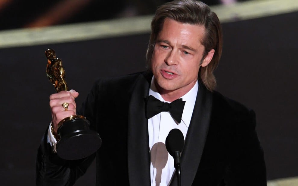 Brad Pitt veste um smoking e segura com a mão direita a estatueta do Oscar, em cerimônica feita em 2020