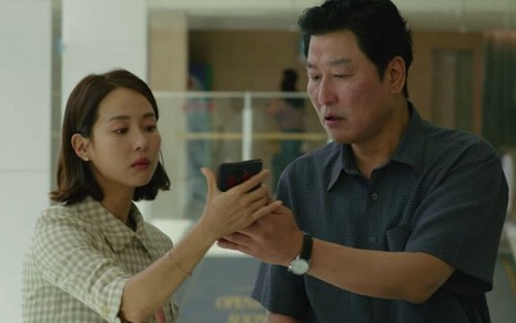 Cho Yeo Jeong e Song Kang Ho observam celular em cena do filme Parasita