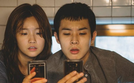 Cena do filme sul-coreano Parasita com dois jovens olhando o celular