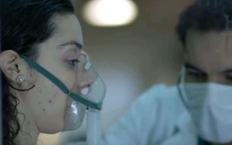 Mulher com máscara no rosto recebendo atendimento médico em cena do documentário Pandemia em Tempo Real