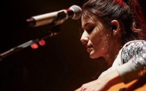 Paula Fernandes tocando violão com um microfone a sua frente
