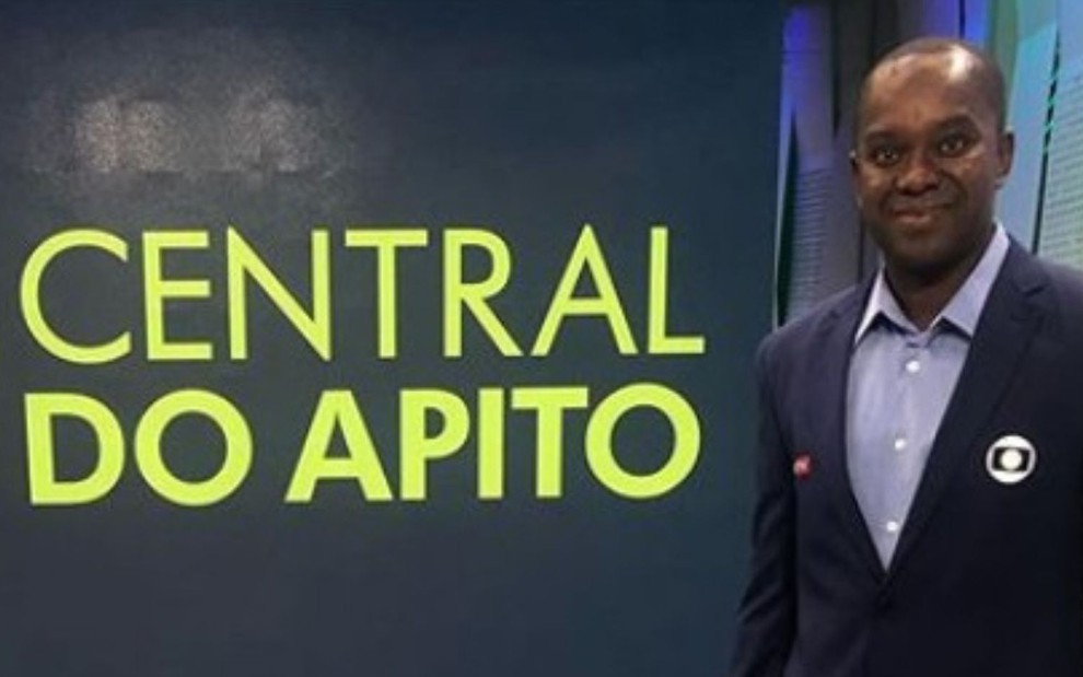 O comentarista de arbitragem da Globo no estúdio de transmissões da emissora, com o logo da Central do Apito ao fundo