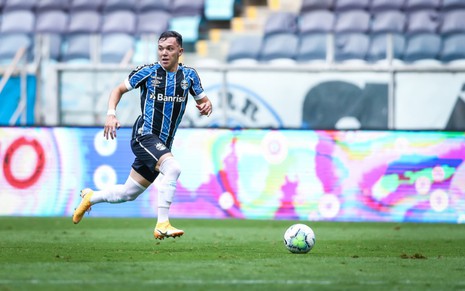 O jogador do Grêmio, Pepê, em lance no campo vestido com o uniforme do time nas cores azul, preto e branco