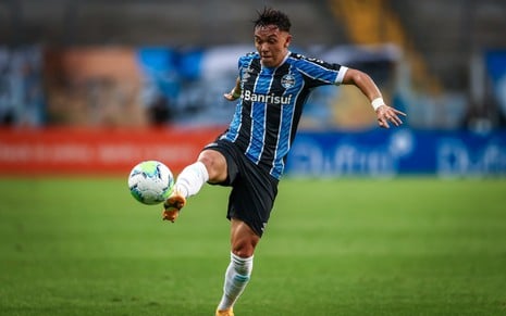 O jogador do Grêmio, Pepê, em lance no campo vestido com o uniforme do time nas cores azul, preto e branco