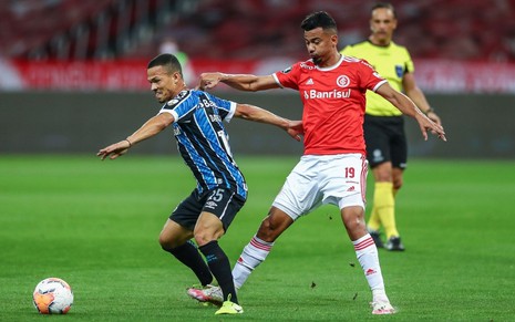 Imagem de Pepê (á esq.) e Rodrigo Lindoso disputando bola durante jogo do Grêmio contra o Internacional na Libertadores 2020