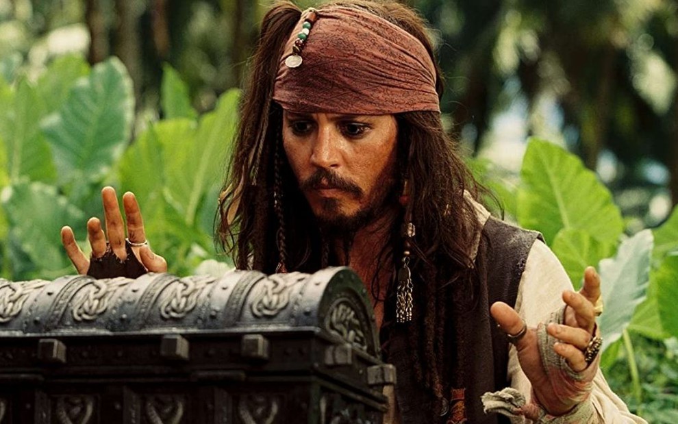 Johnny Depp como o capitão Jack Sparrow olhando o baú em cena de Piratas do Caribe - O Baú da Morte