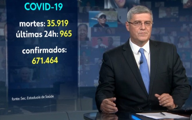 O âncora Flávio Fachel no estúdio do Jornal Nacional, com painel com dados da Covid-19 no Brasil