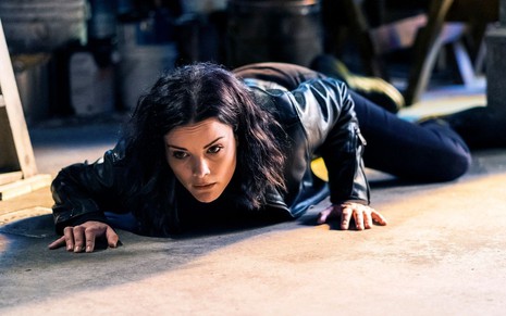 Com uma roupa preta, Jaimie Alexander se arrasta pelo chão em cena de fuga da quinta temporada de Ponto Cego