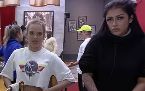 Nina olha para frente, usa camiseta branca e está com o cabelo preso; Fernanda Medrado usa blusa preta, olha para frente e está com o cabelo preso