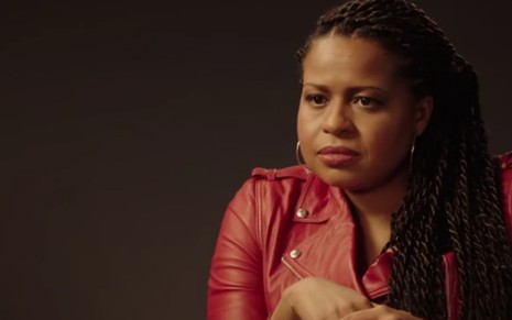 Com cabelo jogado em cima do ombro esquerdo, Courtney A. Kemp veste uma jaqueta vermelha em entrevista sobre a série Power
