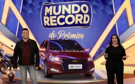 Wellington Muniz, o Ceará, e Fabíola Gadelha em chamada do Mundo Record de Prêmios, com um carro ao fundo