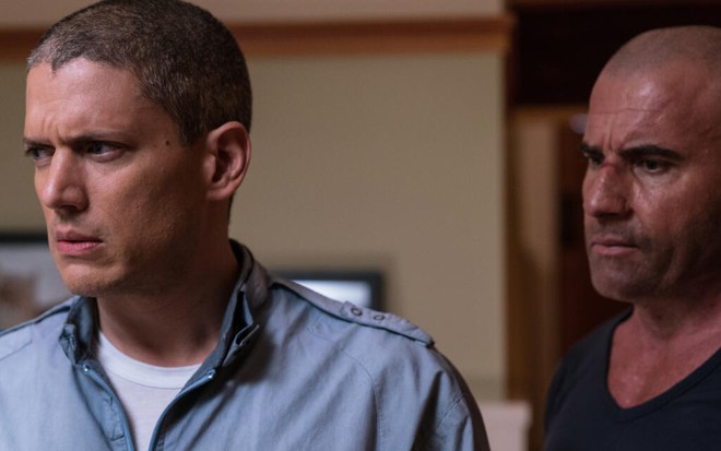Wentworth Miller veste uma camisa azul clara e está à frente de Dominic Purcell, de camiseta preta, em Prison Break