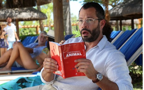 Malvino Salvador se assusta com livro na mão em cena do filme Qualquer Gato Vira-Lata 2