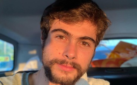 Rafael Vitti de barba, dentro do carro, com o sol refletido no rosto