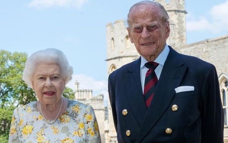 Rainha Elizabeth 2ª de vestido com estampa amarela, ao lado do Príncipe Philip, de terno e gravata