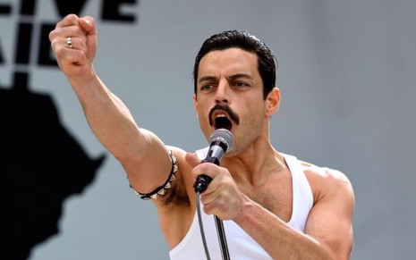 O ator Rami Malek caracterizado como o cantor Freddie Mercury em Bohemian Rhapsody (2018); ele segura um microfone e canta