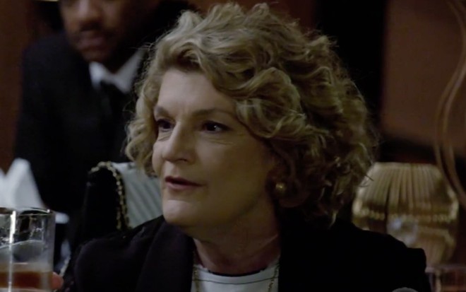 Beth Zalcan em cena de Amor Sem Igual: caracterizada como Carmem, personagem olha com curiosidade para alguém fora do quadro