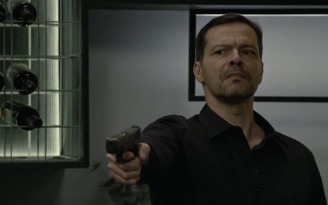 O ator Heitor Martinez segura uma arma com a mão direita e está caracterizado como Bernardo em cena de Amor Sem Igual