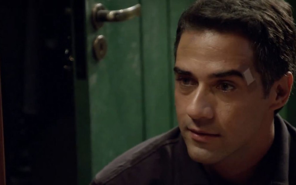 O ator Rafael Sardão em cena como o Miguel de Amor Sem Igual, ele está ajoelhado e tem um curativo ao lado da sobrancelha direita