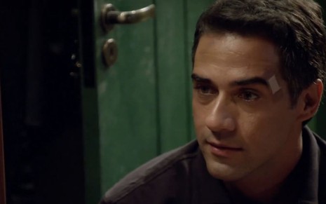 O ator Rafael Sardão em cena como o Miguel de Amor Sem Igual, ele está ajoelhado e tem um curativo ao lado da sobrancelha direita