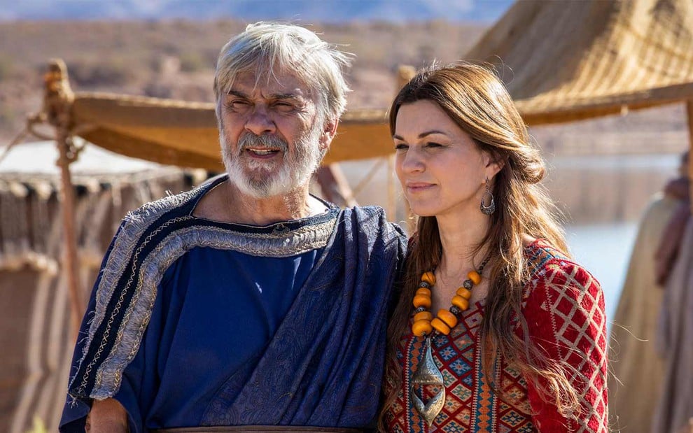Zécarlos Machado e Adriana Garambone em cena de Gênesis: caracterizados como Abraão e Sara, casal sorri e olha para o deserto