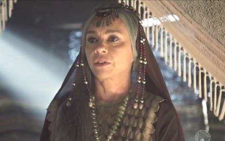 Carla Marins interpreta Adália em cena Gênesis: atriz olha com seriedade para alguém fora do quadro