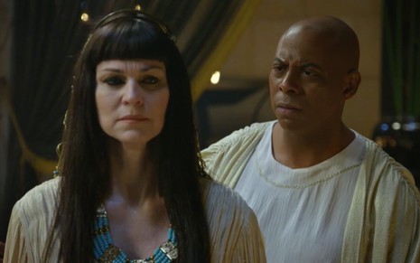 A atriz Adriana Garambone com vestes egípcias, com uma peruca de cabelos pretos e lisos, tenta não olhar para André Ramiro como Amenemhat 3º em cena de Gênesis