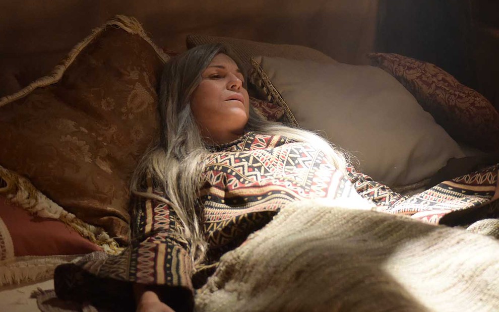 A atriz Adriana Garambone está deitada em uma cama, nas últimas, como a Sara em cena de Gênesis