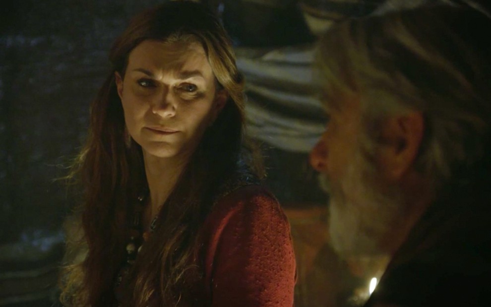 A atriz Adriana Garambone como Sarai em uma cena noturna de Gênesis dentro de uma tenda, ela tem uma expressão tristonha