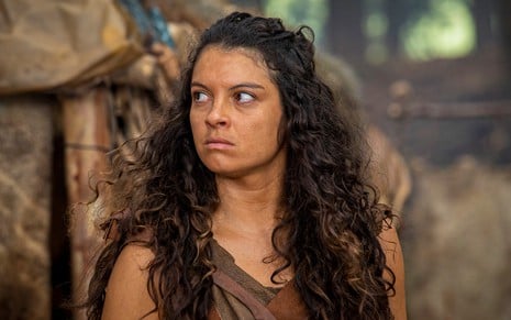 A atriz Ana Terra olha para a direita com expressão enfezada e está caracterizada como Renah em cena de Gênesis
