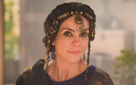 Flávia Monteiro caracterizada como Aya em Gênesis: com adorno dourado na cabeça, atriz usa maquiagem preta ao redor dos olhos e sorri para câmera